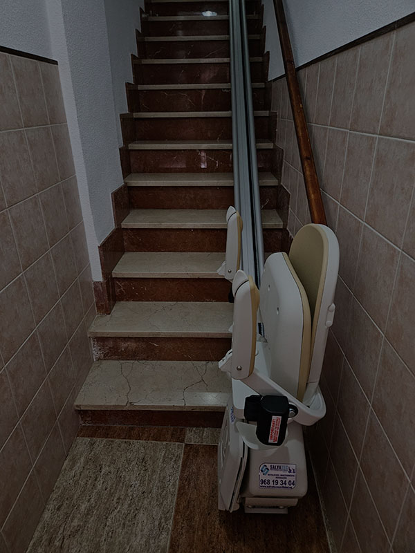 Silla salvaescaleras plegada, al principio de una escalera estrecha de acceso a una vivienda