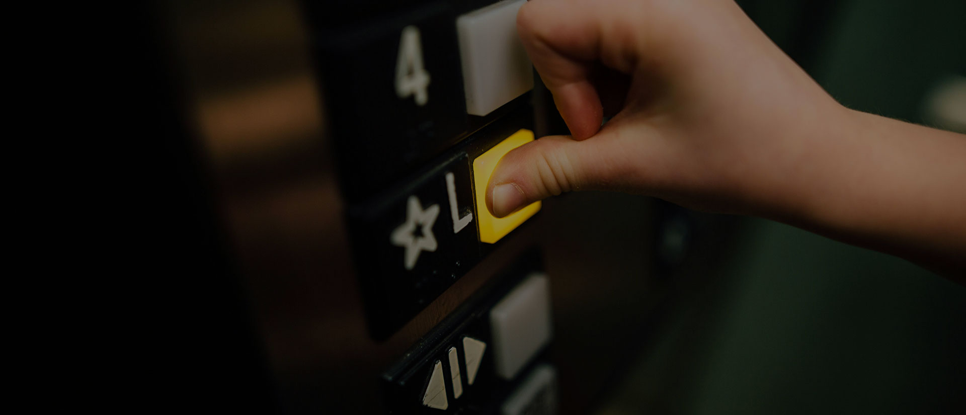 Primer plano de una mano de mujer pulsando un botón amarillo de ascensor