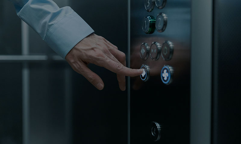 Primer plano de mano de hombre apretando un botón de ascensor