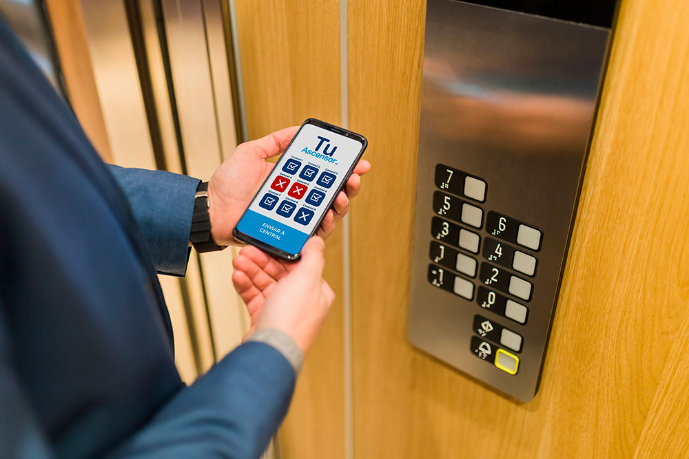 mantenimiento02 Manos de hombre sosteniendo un móvil delante de los botones de un ascensor