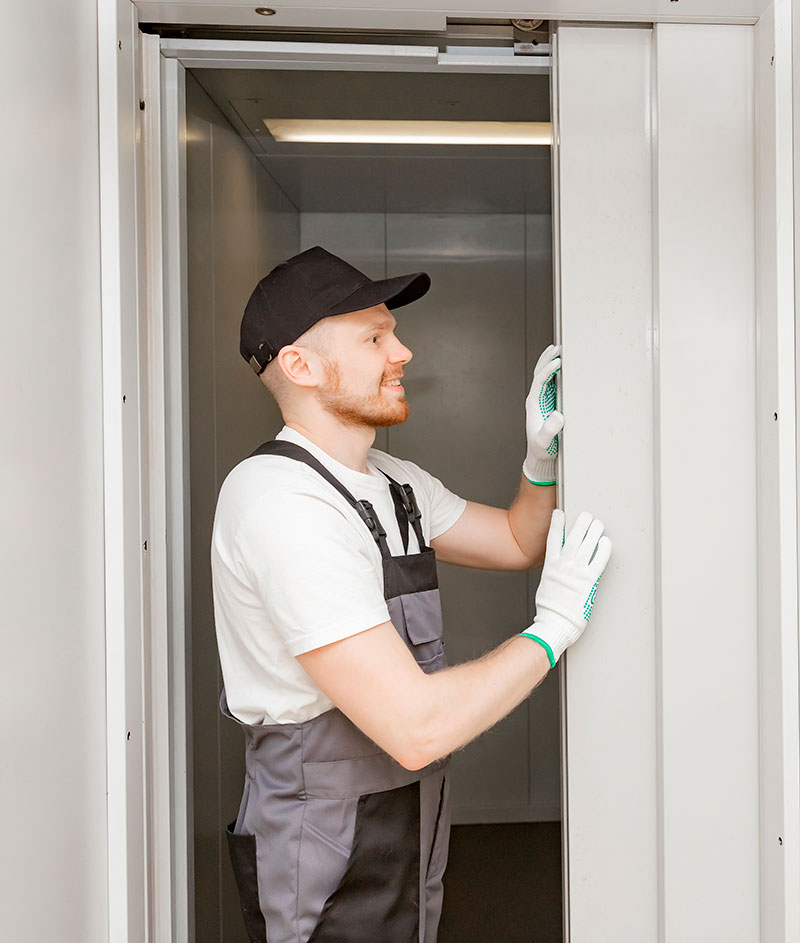 Operario de mantenimiento de ascensores revisando la puerta de un ascensor