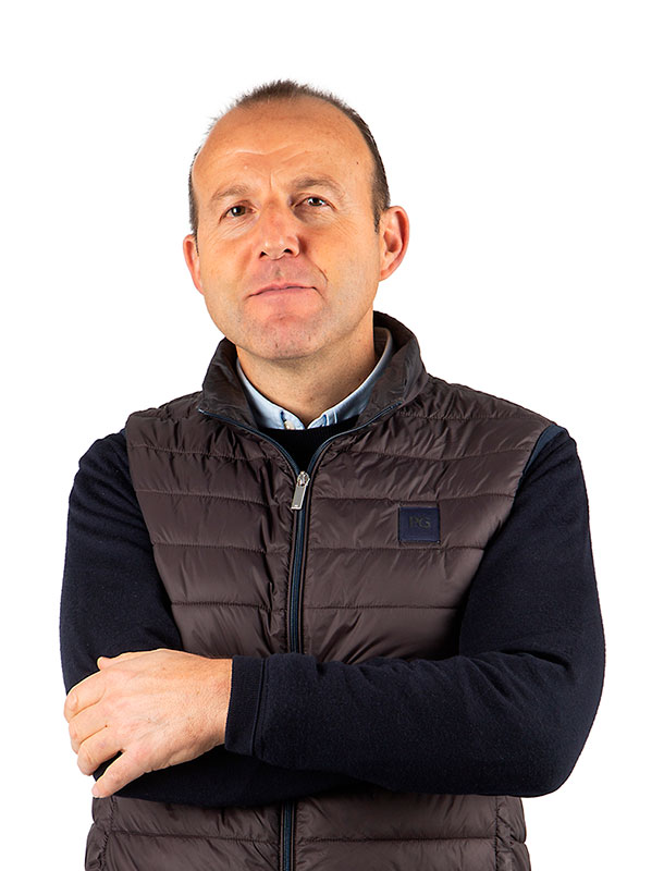 Hombre de mediana edad con camisa, jersey y chaleco, mirando directamente a la cámara